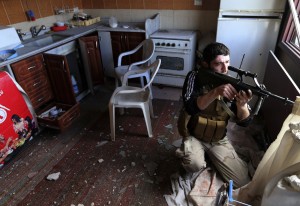 Un combattant des forces rebelles, posté à l'intérieur d'une maison à Damas, riposte aux tirs de l'armée syrienne. Cette scène se déroulait le 22 janvier dernier (photo CNS/Goran Tomasevic/Reuters).