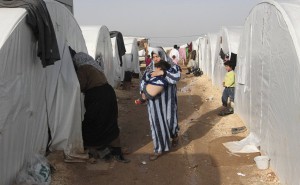 Syrian refugee woman carries child at refugee camp near Turkish border