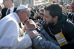 En chemin pour la célébration de la messe inaugurale de son pontificat, le pape François, de sa papemobile sur la Place St-Pierre, aperçoit un homme lourdement handicapé. Il demande alors d'arrêter le véhicule pour descende et embrasser l'impotent (photo CNS/L'Osservatore Romano).