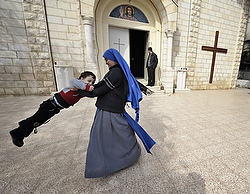 Une religieuse de la communauté du Verbe Incarné s'amuse avec un enfant à la sortie de la messe dominicale à l'église de la Sainte-Famille de la Bande de Gaza. Il n'y a que quelque 200 catholiques sur les 3000 chrétiens à Gaza (photo CNS/Paul Jeffrey).
