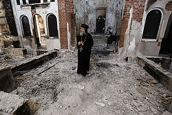 Un évêque copte orthodoxe observe les dommages causées à l'église lors des soulèvements en août dernier (photo CNS/Louafi Larbi, Reuters).